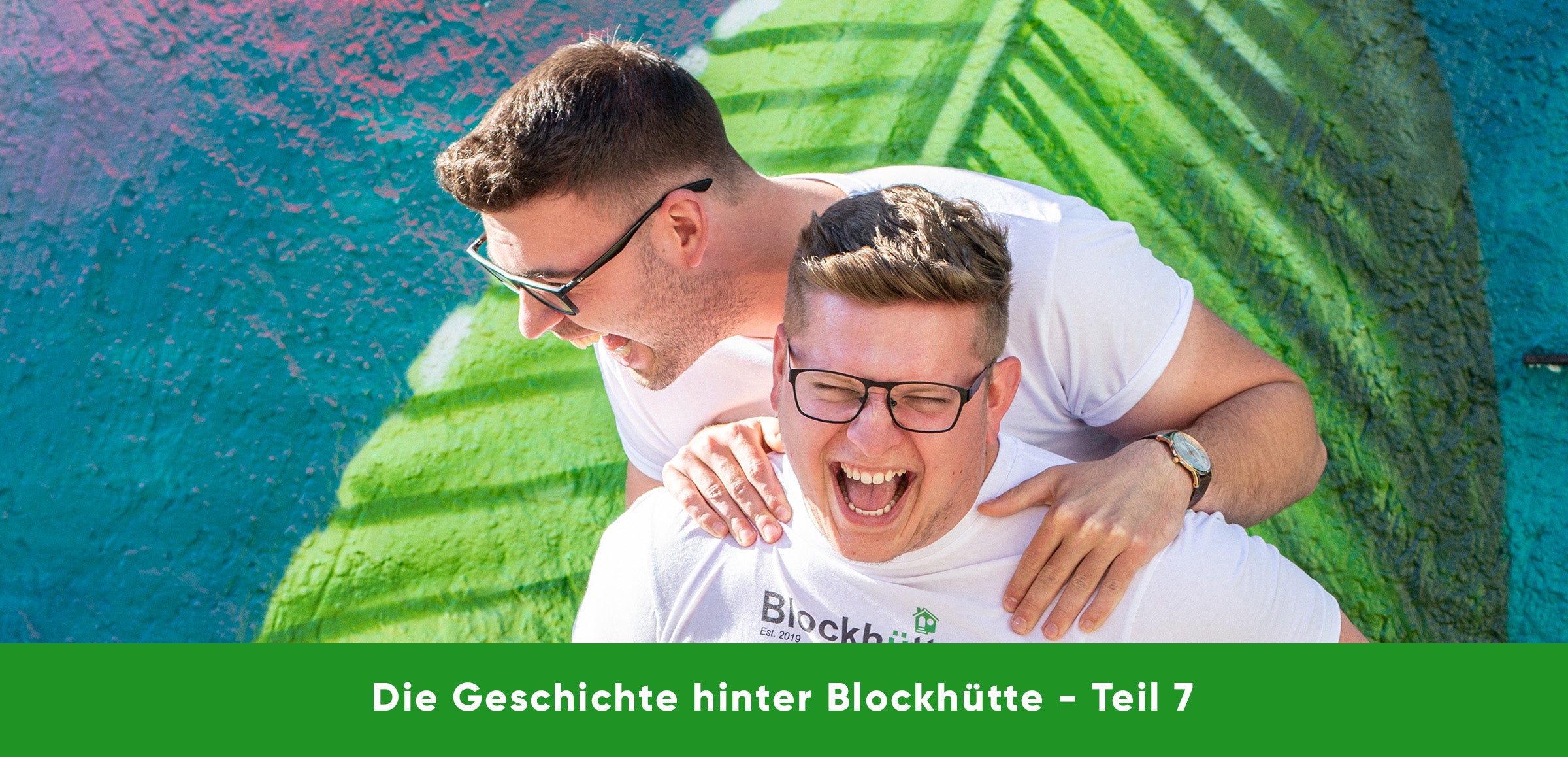 Nils trägt Malte huckepack, beide lachen. Blockhütte Edelstahl